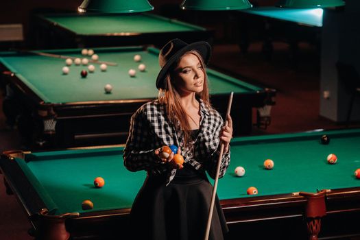 A girl in a hat in a billiard club with a cue in her hands.billiards Game