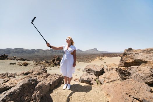 a stylish woman takes a selfie in the crater of the Teide volcano. Desert landscape in Tenerife. Teide National Park. Desert crater of the Teide volcano. Tenerife, Canary Islands