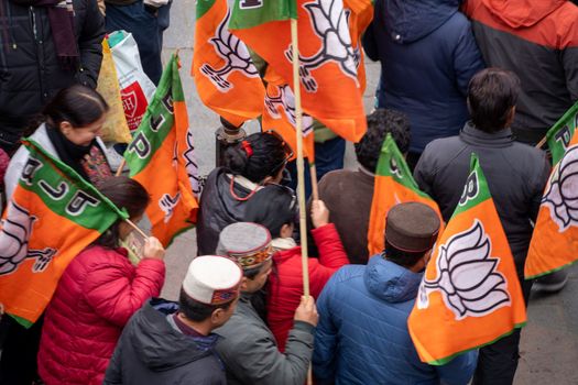 aerial drone shot crowd people with saffron flags of BJP protesting or celebrating victory in hill station manali standing in circle with leader