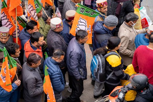 aerial drone shot crowd people with saffron flags of BJP protesting or celebrating victory in hill station manali standing in circle with leader
