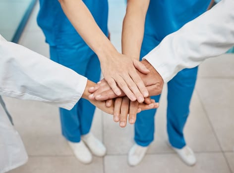 We have the team spirit. a group of unrecognizable doctors stacking their hands at a hospital.