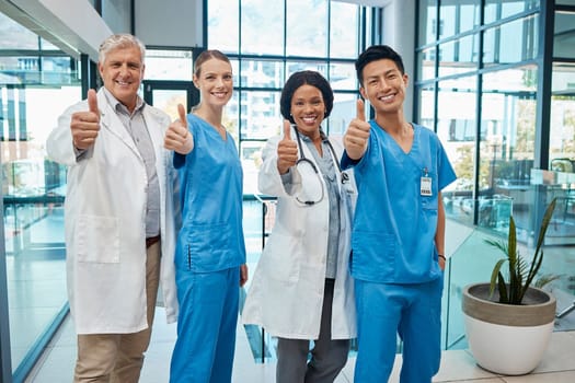 We aim to give you good healthcare. a group of doctors showing a thumbs up at a modern hospital.