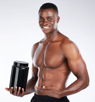 This is pure muscle in a bottle. a handsome young man standing alone in the studio and holding a container of whey protein.