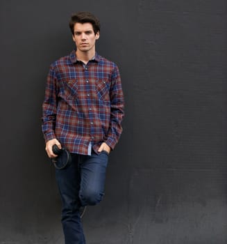 Laid back in plaid. a handsome young man standing outdoors with his earphones.