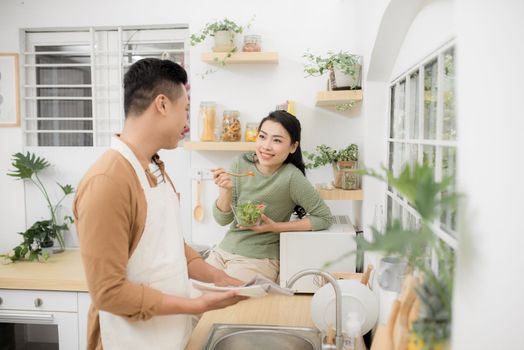 Asian couple eating breakfast early in the morning in the kitchen and having a good time.