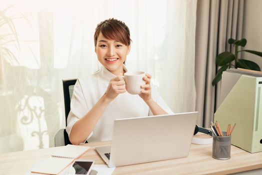 Young Asian businesswoman entrepreneur working on laptop from home office space