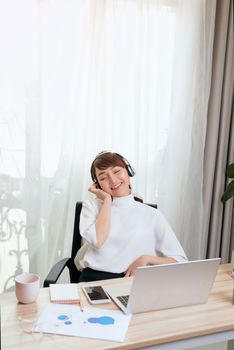 Young Asian woman in headphones working on the computer at home