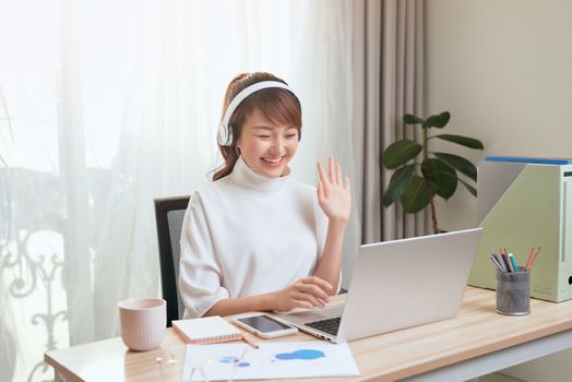 Beautiful Asian woman calling video by laptop at working place home.