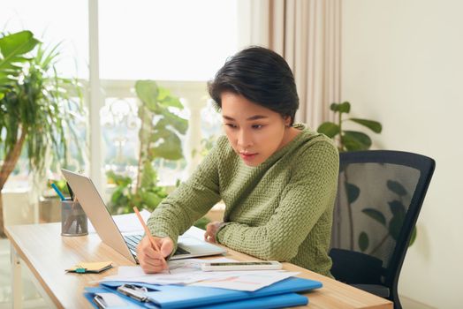 Young Asian businesswoman focusing on her documents 