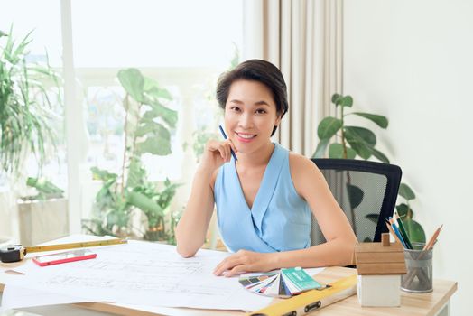 Portrait of young Asian architect sitting in her office