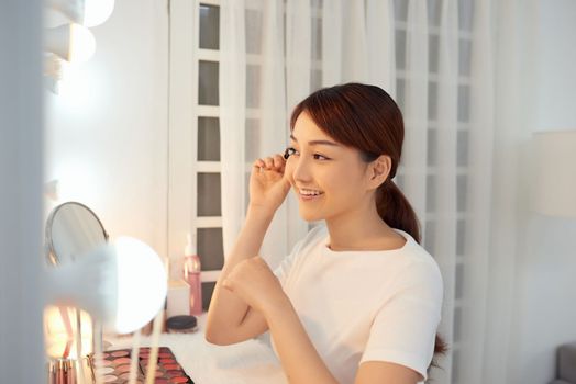 Beautiful Asian woman applying mascara for her eyelashes