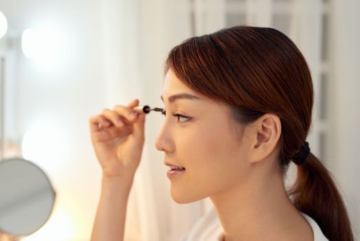 Closeup Of Beautiful Asian Woman Putting Black Mascara On Eyelashes. Beauty Cosmetics. 