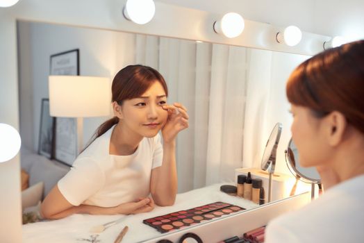 Unhappy young Asian woman in front of a mirror looking at her wrinkles
