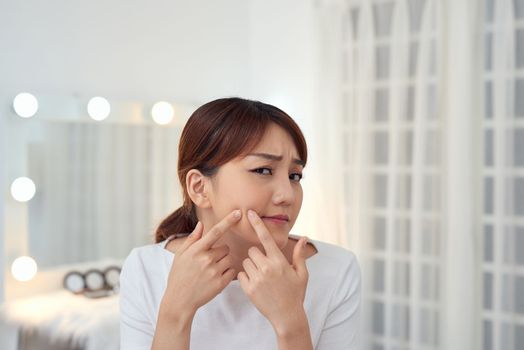 Young Asian woman squeeze her acne