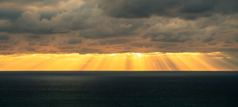 Sunbeams by the sea of clouds baner. Seascape with dark clouds and the rays of the sun from them.