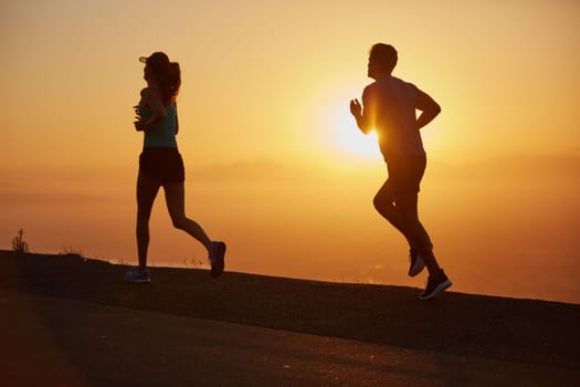 Chasing fitness goals. a silhouetted couple out for a run at sunrise