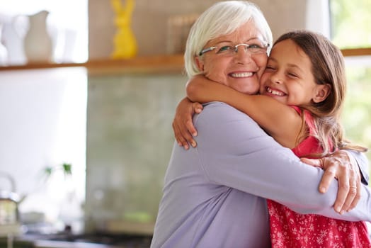 Grandmas and grandchildren share a special bond. Portrait of a cute little girl hugging her grandmother in a kitchen.