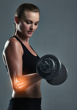 Its time to build some muscles. Studio shot of a sporty young woman building muscle in her arms.