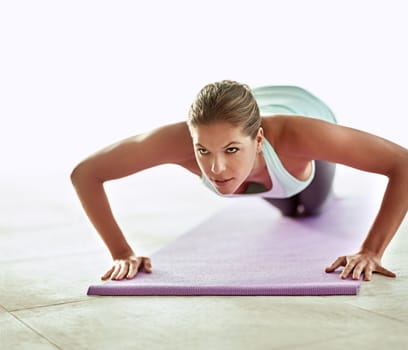 Working those core muscles. a young woman doing push-ups during a workout.