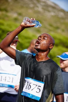 Remember to hydrate. a young male runner pouring water over himself after a road race.