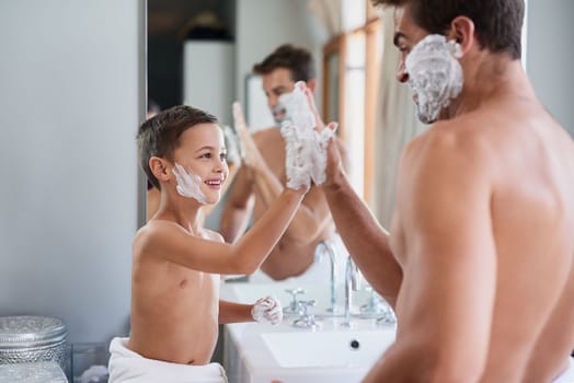 Attaboy. a handsome young man teaching his son how to shave in the bathroom.