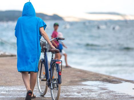 woman riding a bicycle and wearing a beach poncho