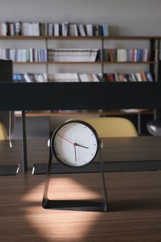 Round clock on table against a library background
