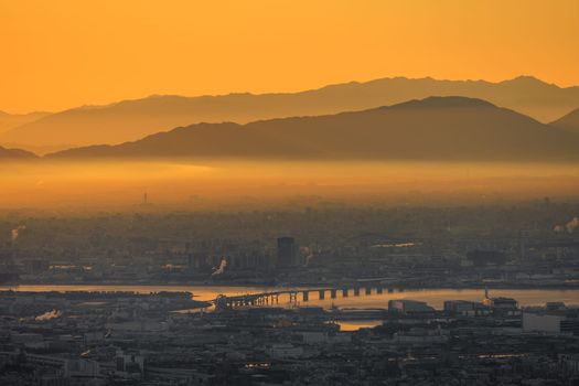Thick layer of smog over industrial city with orange glow in sky at dawn