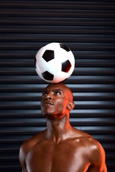 Great champions always remain level headed. Studio shot of an athletic young man playing with a soccer ball against a grey background.