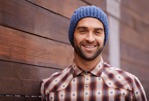 Keep it casual. Portrait of a handsome young man in trendy winter attire against a wooden background.