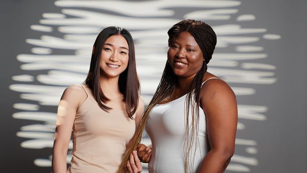 Interracial unique women creating beauty ad in studio