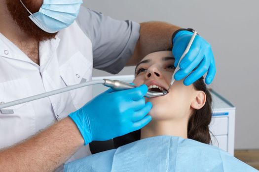 Dentist drilling tooth of female patient in dental chair