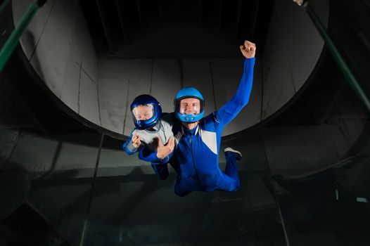 A man teaches a boy to fly in a wind tunnel. Lack of gravity.