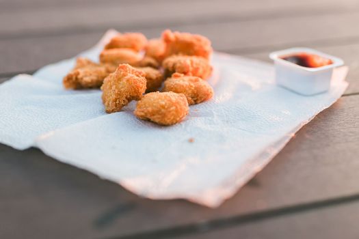 Chicken nuggets with sauces on napkin on wooden background outdoor meal - fast food, junk food and picnic concept