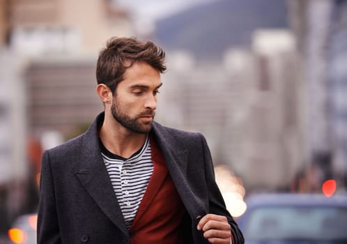 Fashioned for winter. a handsome young man taking a walk through the city.