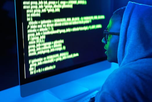 Hes one hack away from his end goal. a young male hacker cracking a computer code in the dark.