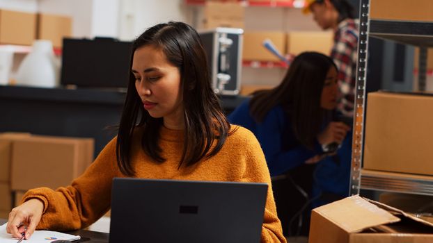Asian employee working on stock logistics with laptop