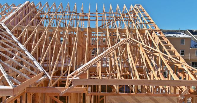 During the construction of a new stick home, a wooden roof beam was constructed from an adjacent framework frame made from trusses.