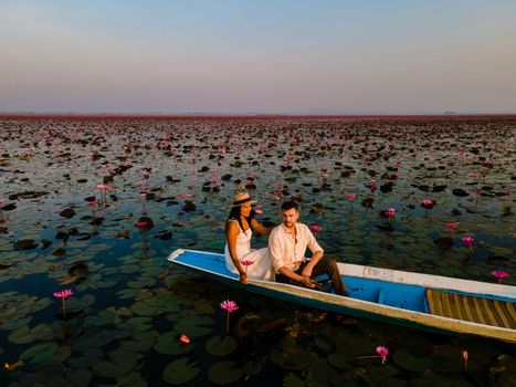 Men and women in a boat at Sunrise at The sea of red lotus, Lake Nong Harn, Udon Thani, Thailand