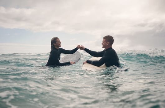 We caught feelings while catching some waves. a young couple out surfing together at the beach.