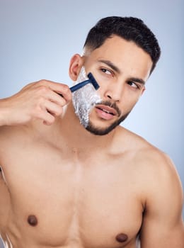 hes about to look like a million bucks. a young man shaving against a studio background.