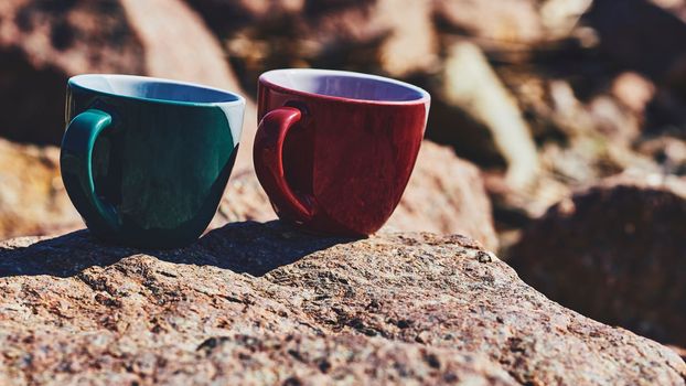 ed green ceramic cups for coffee tea beverages on a rocky sunny stones
