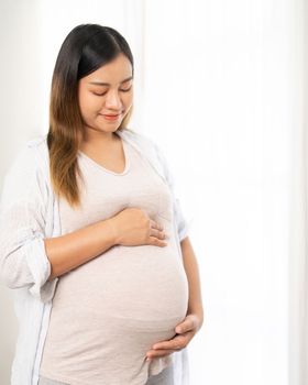 pregnant woman standing near window at home
