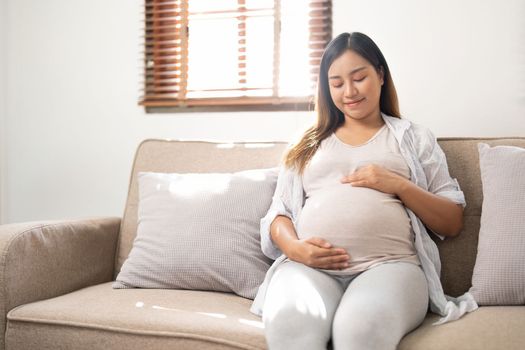 pregnancy, rest, people and expectation concept - close up of happy smiling pregnant woman in and touching her belly at home
