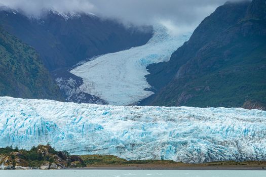 Amalia Glacier towers over large rocks and trees in Patagonia