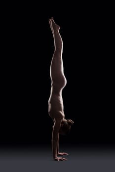 Nude gymnast posing in dark studio