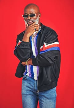 Hes the OG around here. Studio shot of a senior man wearing retro attire while posing against a red background.