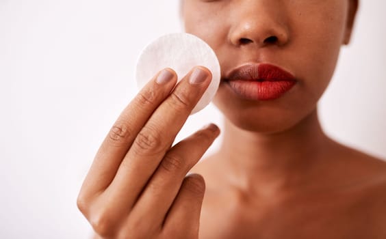 This is all I use to remove my makeup. Studio shot of an unrecognizable woman using a cotton pad to remove her lipstick.