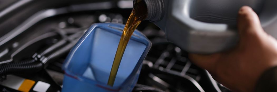 Auto mechanic replaces and pours fresh oil into engine at service station