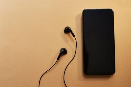 Turn the world off, turn the music on. Studio shot of a smartphone and earphones against a brown background.